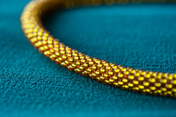 Fragment of a golden necklace on a green textile background