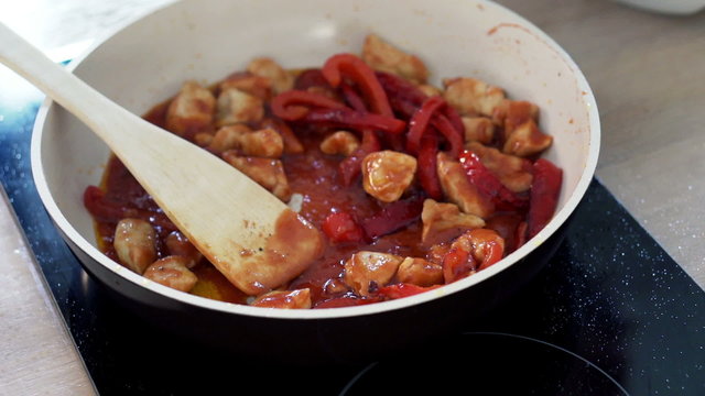 Cooking, mixing chicken, pepper and olives on pan, closeup
