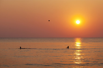 at sunset, playing with a ball