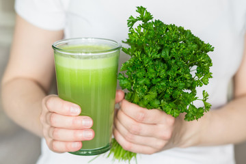 A glass of apple juice and celery bunch parsley