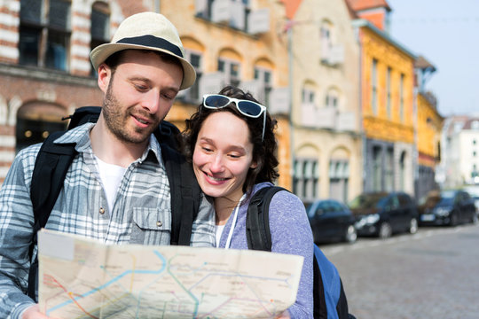 Couple of young attractive tourists watching map