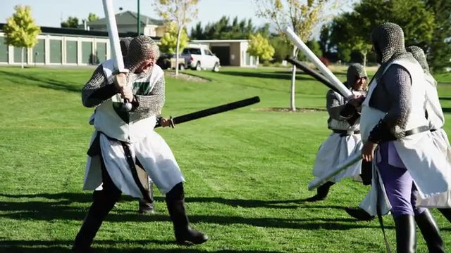MS Group of men wearing historical clothing fighting with swords in park / Orem,Utah,USA