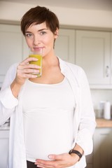 Fototapeta premium Pregnant woman drinking glass of orange juice