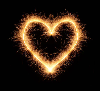 Bright romantic love heart drawn with sparkles isolated on black