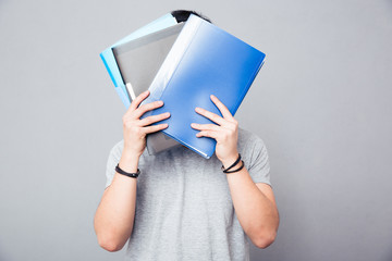 Man covering his face with folders
