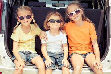 Happy brother and his two sisters are sitting in the car