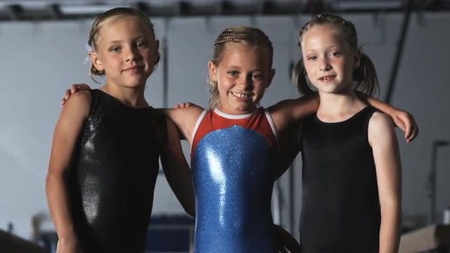 MS TU Portrait of three smiling girls (8-9) wearing leotards in gym, Orem, Utah, USA