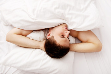 Handsome young man lying in bed.