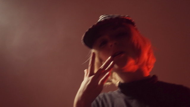 Girl in a cap moving in the studio in the smoke