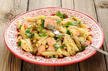 Creamy pasta with salmon and parsley in red plate