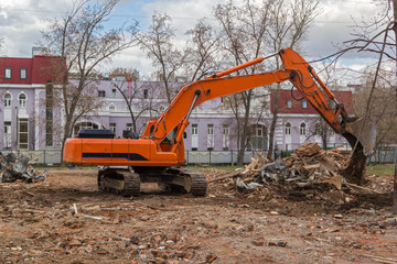 Fototapeta na wymiar excavator removes construction waste after building demolition