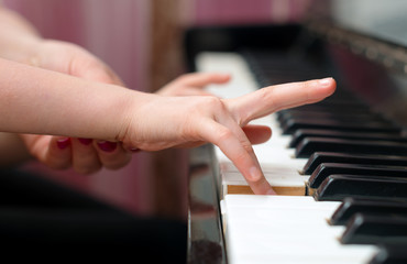 Woman teaches the child to play the piano.