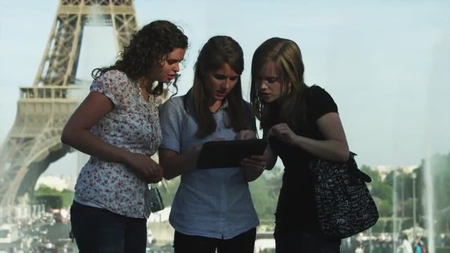 MS Young women reading guidebook in front of Eiffel Tower / Paris, France