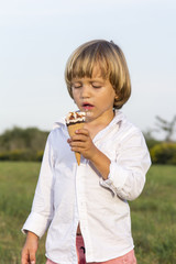 Young cute blond boy eating a tasty ice cream