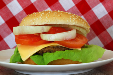 Cheeseburger on red and white checkered cloth, closeup