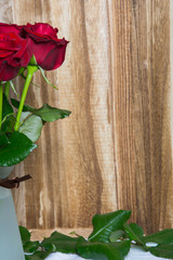 Red roses on wooden background with space for text