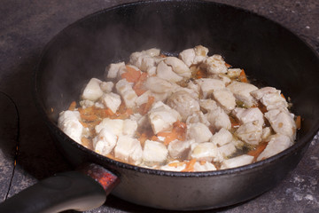 Grilled meat with vegetables in a pan on a hot  plate during coo