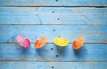 Fototapeta na wymiar cocktail umbrellas, on blue planks background, free copy space