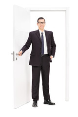 Young businessman posing in front of a door