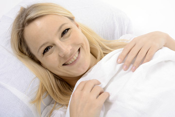 Frau im Bett liegt unter Decke