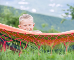 Portrait happy smiling little boy lying in hammock