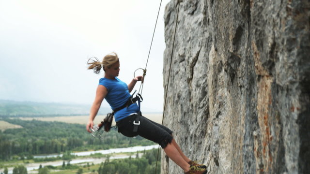 woman repelling down a cliff face