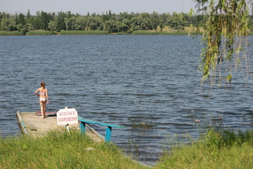 Девочка на старом пирсе у озера © Roman TINIAKOV