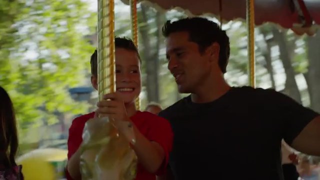 Close up of father and son riding carousel at carnival / American Fork, Utah, United States