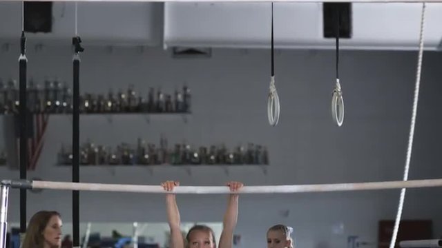 WS Female instructor assisting girl (10-11) exercising on bars, Orem, Utah, USA