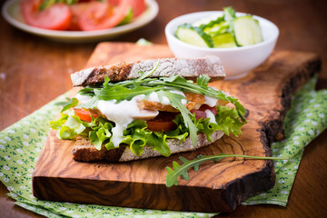 Rye toast sandwich with green leaf, tomato and chicken