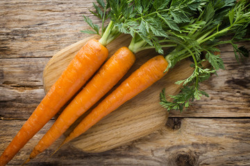 Fresh carrots on the wooden background.