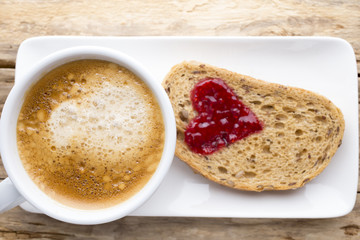 Fresh coffee. Grain slice of bread with jam heart shape.
