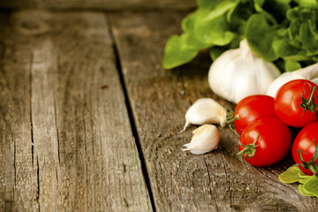 green salad, tomatoes and garlic on a wooden background
