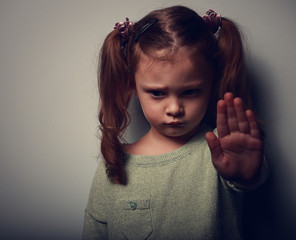 Kid girl showing hand signaling to stop violence and looking dow