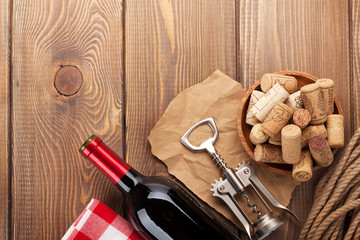 Fototapeta na wymiar Red wine bottle, corks and corkscrew over wooden table backgroun