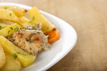 Roasted chicken with potatoes and herbs on white plate