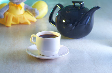 Coffee cup and kettle with blurred toy