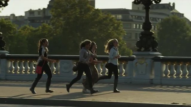 Tracking shot of tourists running on Paris bridge / Paris, France
