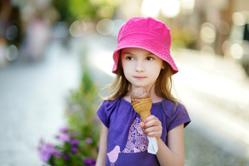 Adorable little girl eating ice-cream outdoors