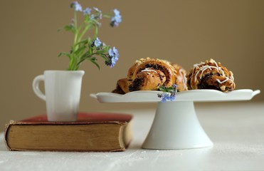 jug with flowers forget-me-not on vintage book and croissants