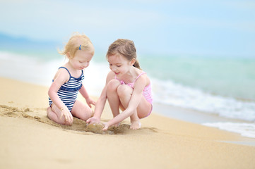 Naklejka premium Two little sisters having fun on a beach