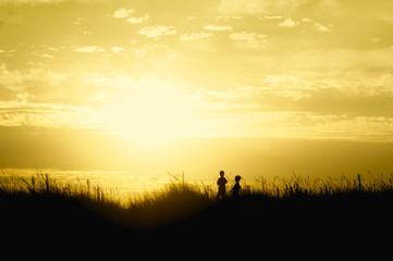 Naklejka na ściany i meble children playing on beach dunes at sunset silhouette