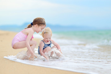 Two little sisters having fun on a beach