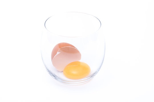 uovo  con guscio rotto in un bicchiere su sfondo bianco
