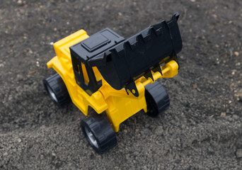 Children's toys excavator with a blade on the field