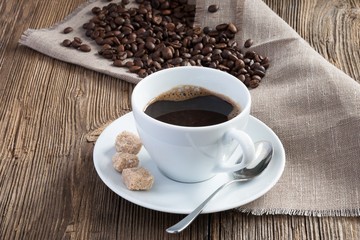 Coffee cup with spoon, coffee beans and cane sugar