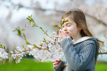 Adorable little girl in blooming cherry garden
