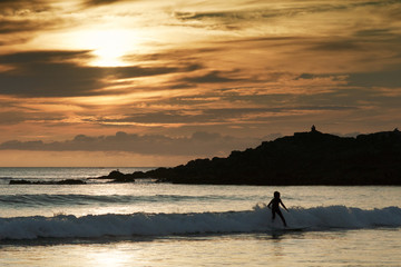 little boy surfer on seashore at sunset in Doninhos beach Galici