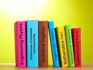 Colorful books on table on color background
