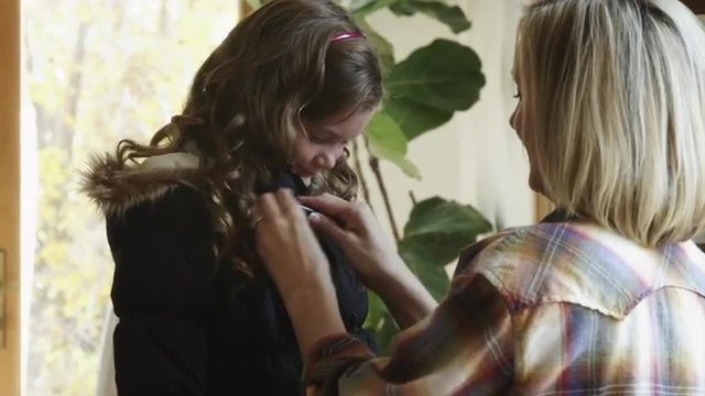 CU Mother helping daughter (8-9) putting on warm jacket / Cedar Hills, Utah, USA